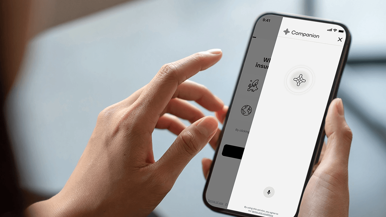 Person holding phone showing Companion app with microphone button on screen.