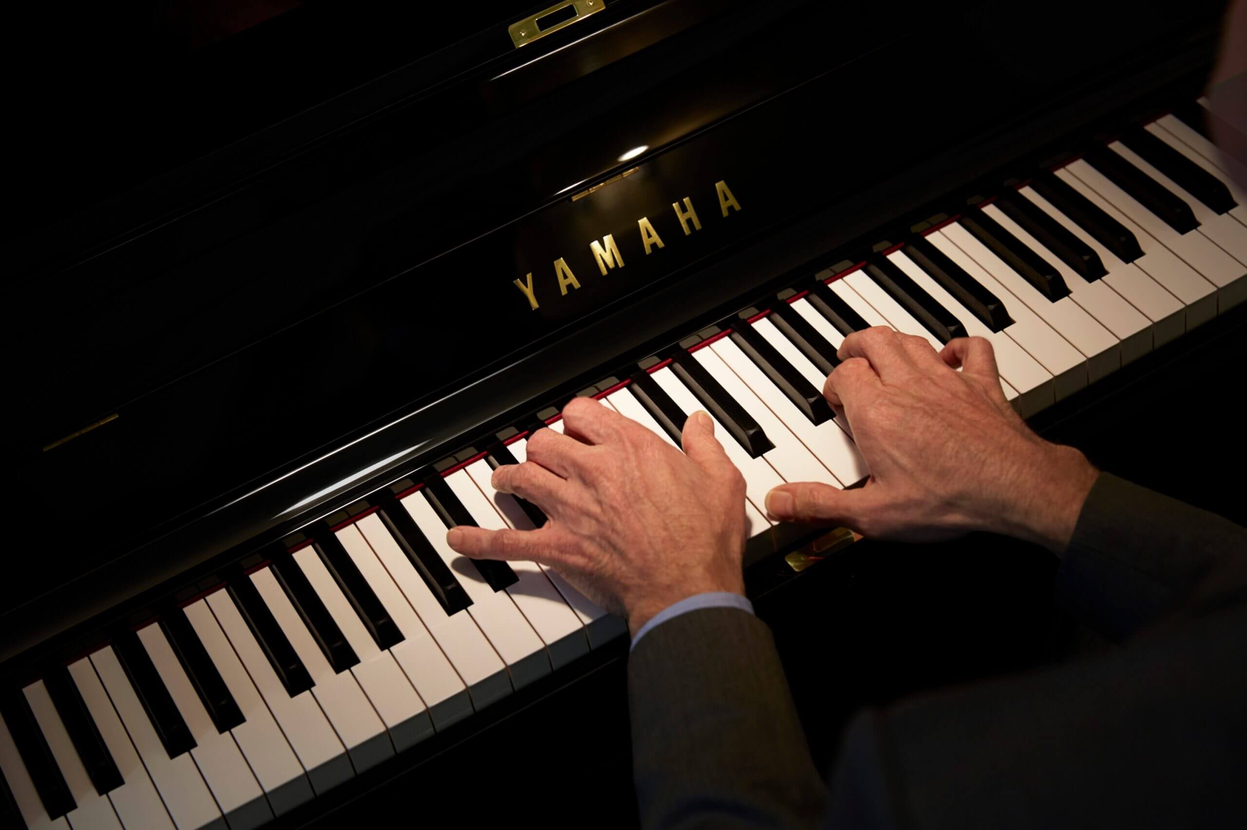 Hands playing keys on a Yamaha piano keyboard.
