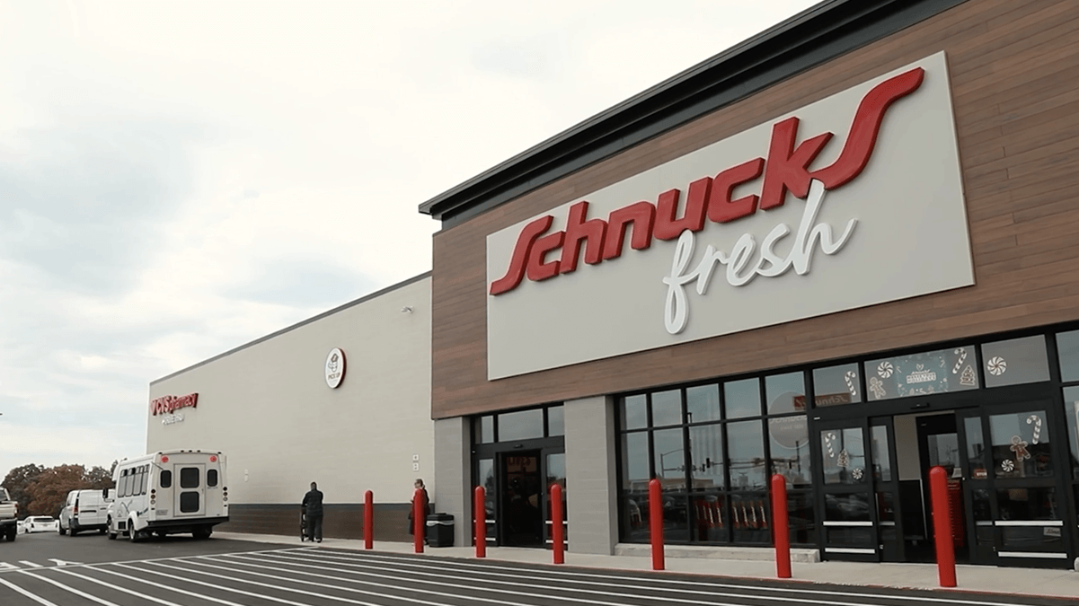 Exterior of Schnucks Fresh grocery store with red sign and glass entrance doors.