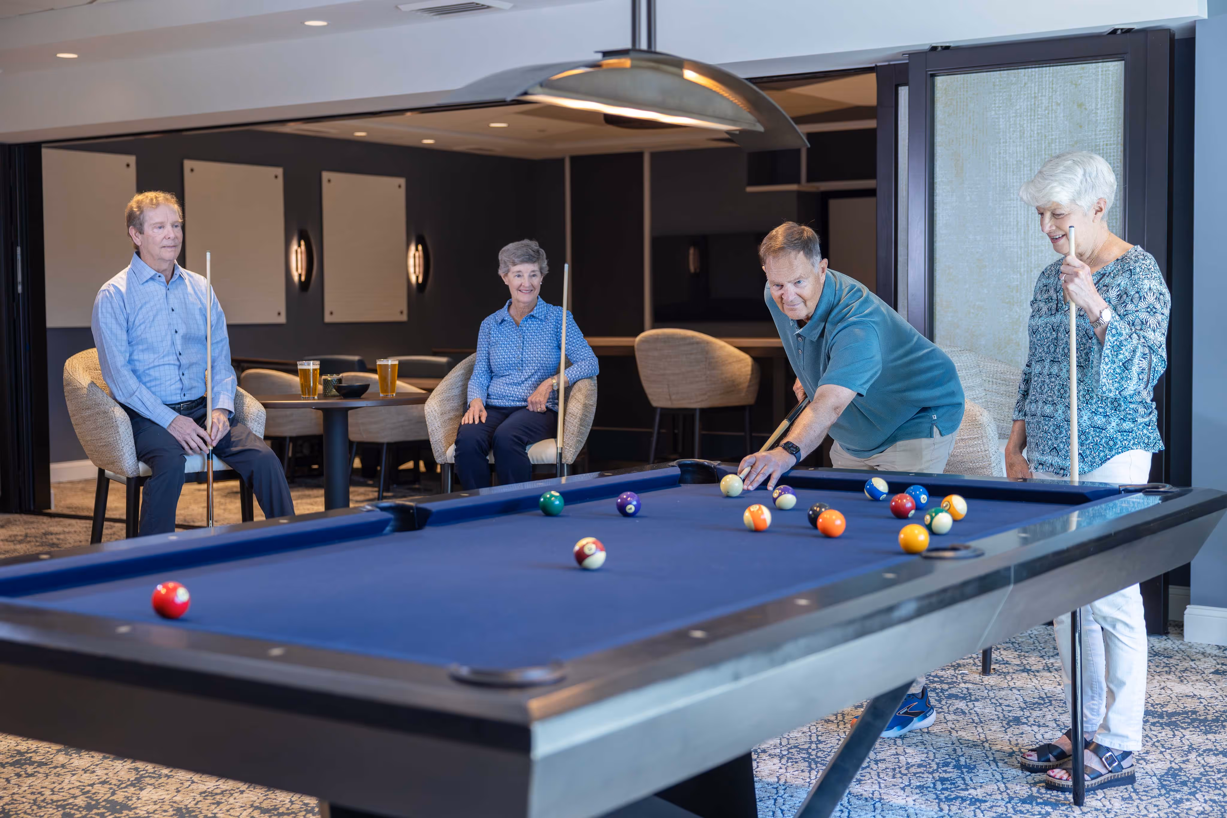 Older adults enjoying a game of pool, smiling and focused as they take turns at the table.