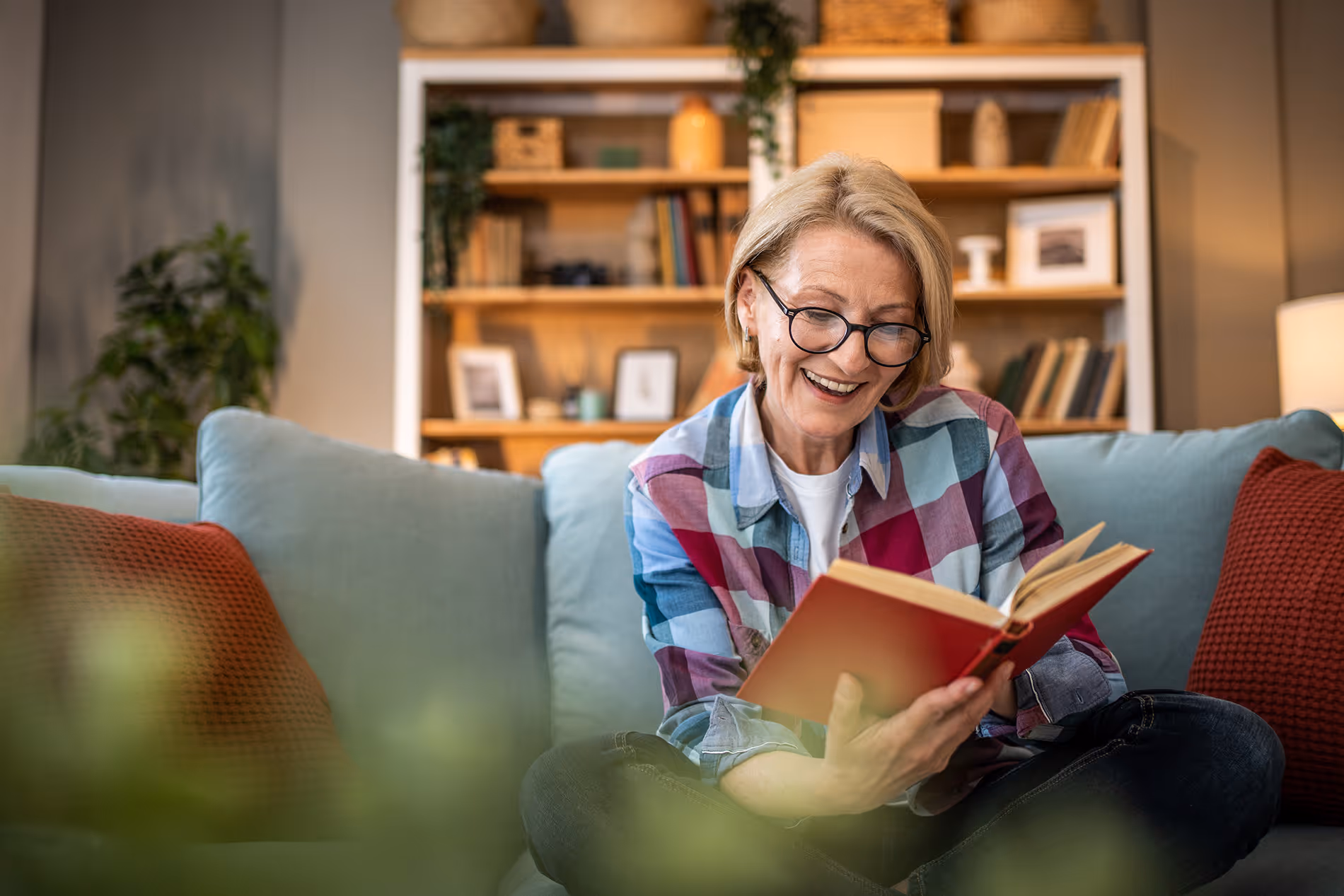 Woman reading a book while surrounded by shelves full of books, fully immersed in her reading.