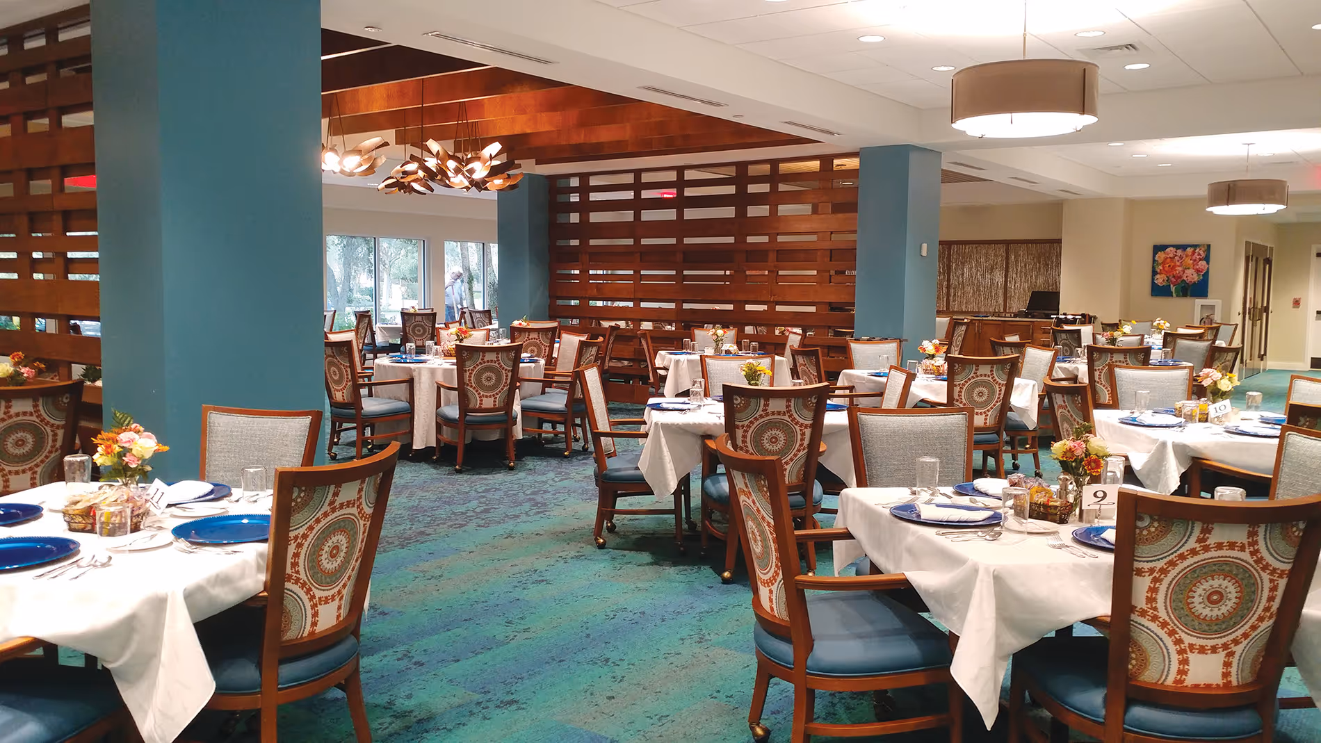 Spacious empty dining room with neatly arranged tables and chairs, natural light streaming through large windows.