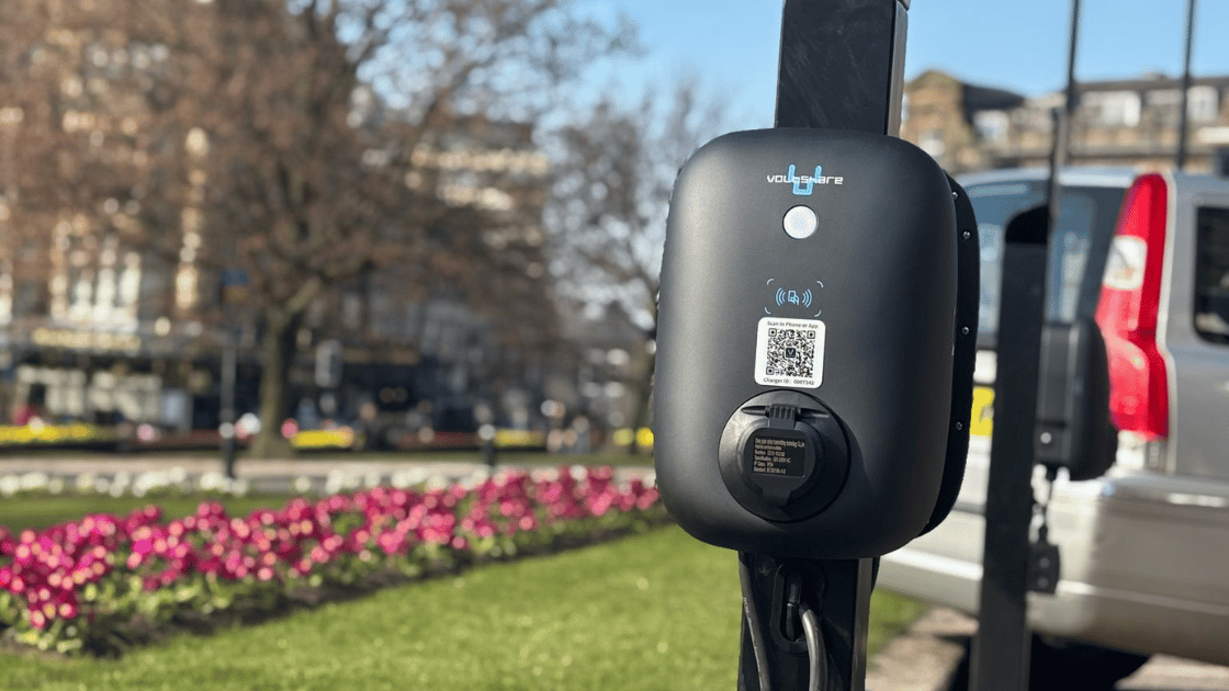 EV charger beside a car park and flowerbed.