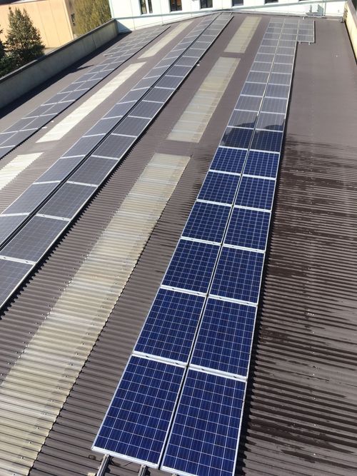 Pannelli solari installati in file su un tetto industriale di lamiera ondulata.