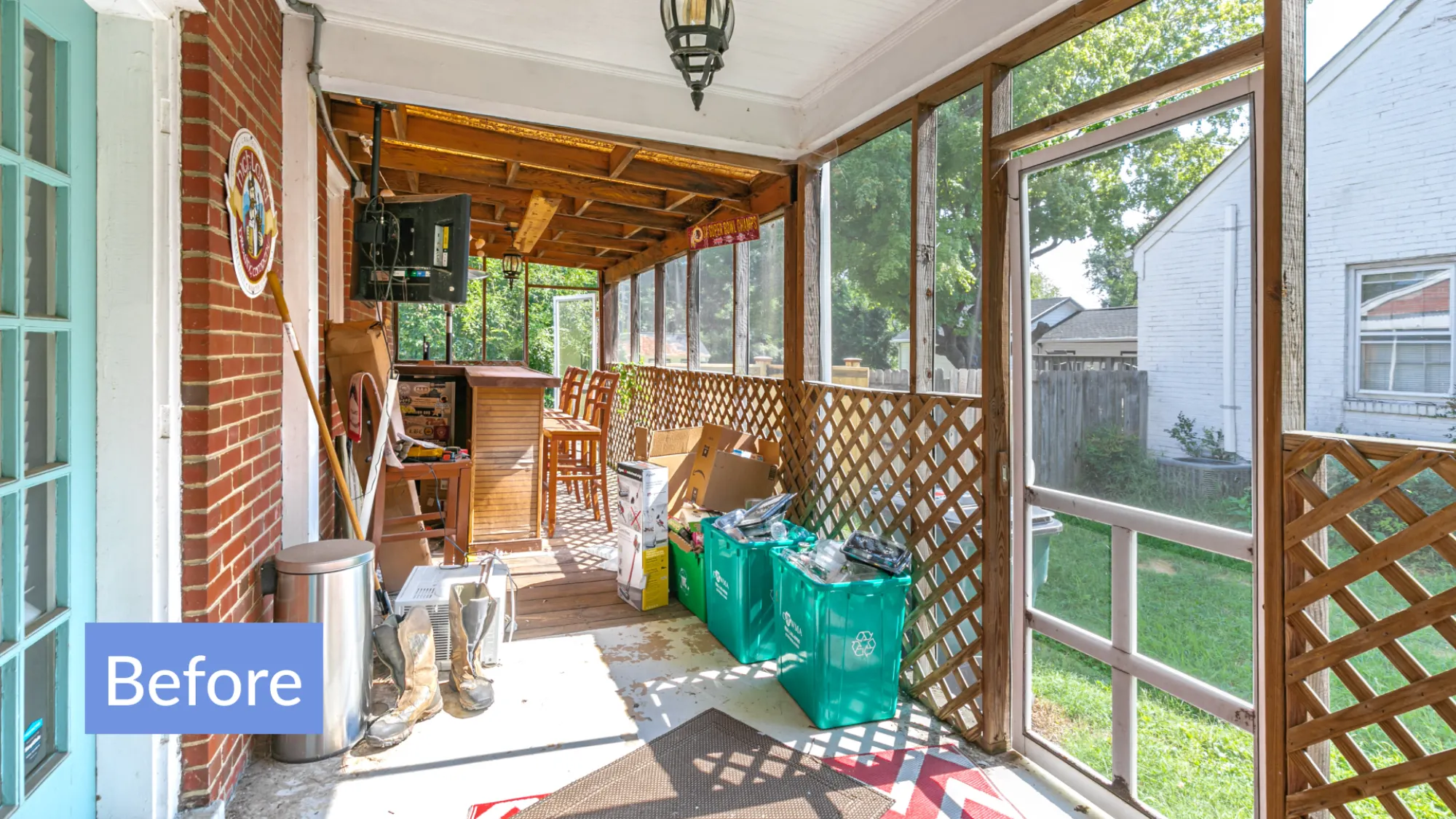 Bright enclosed porch with wooden lattice walls cluttered with recycling bins, boxes, boots, bar stools, and a TV.