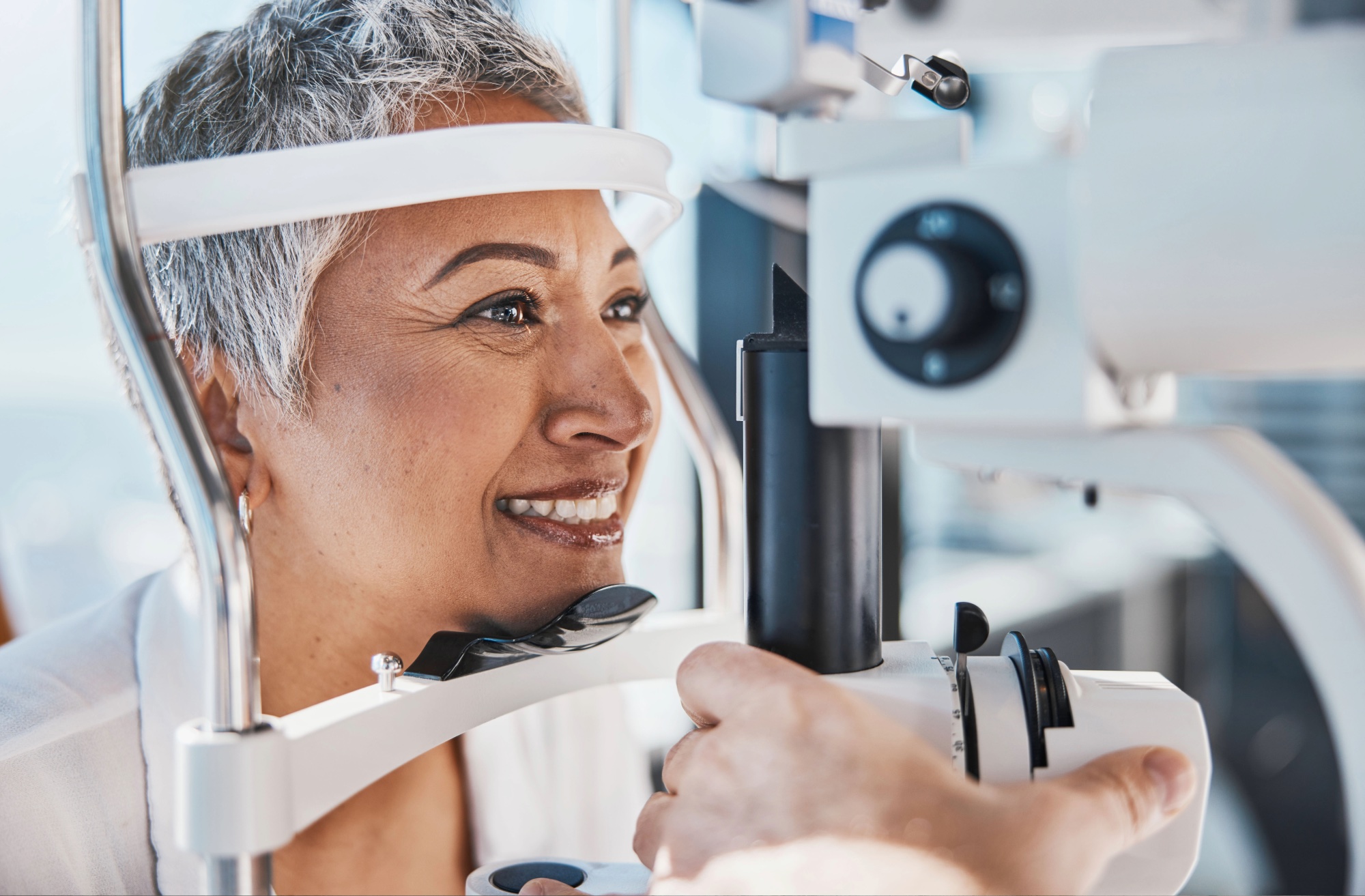 Woman undergoing an eye exam with a slit lamp at an optometrist's office.
