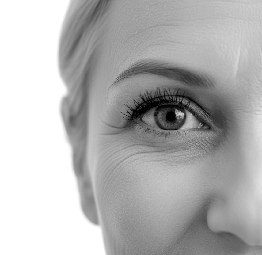 Close-up of a woman's eye with detailed eyelashes and fine facial lines, in black and white.