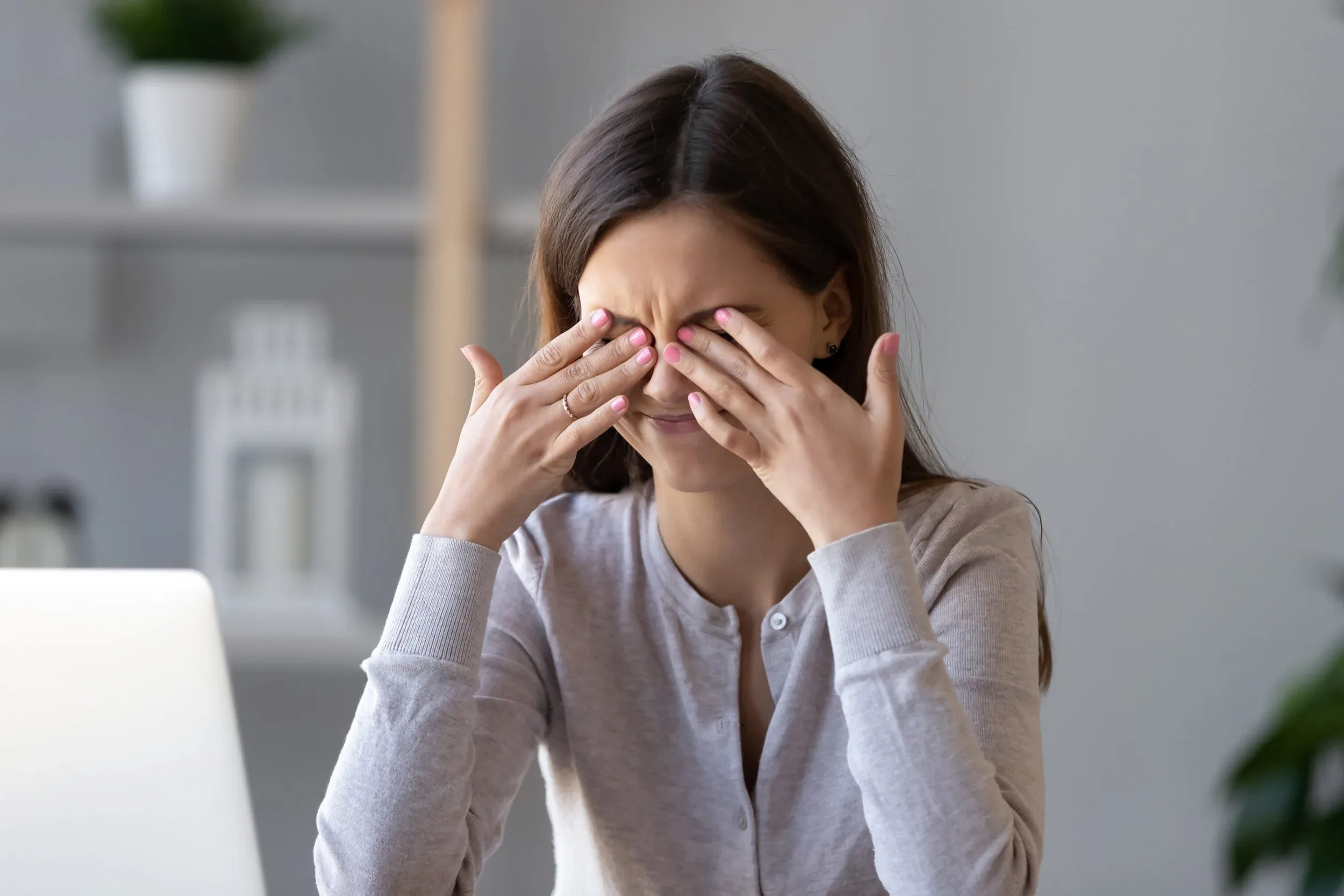 Woman rubbing her eyes with both hands, appearing to have eye discomfort or allergies.