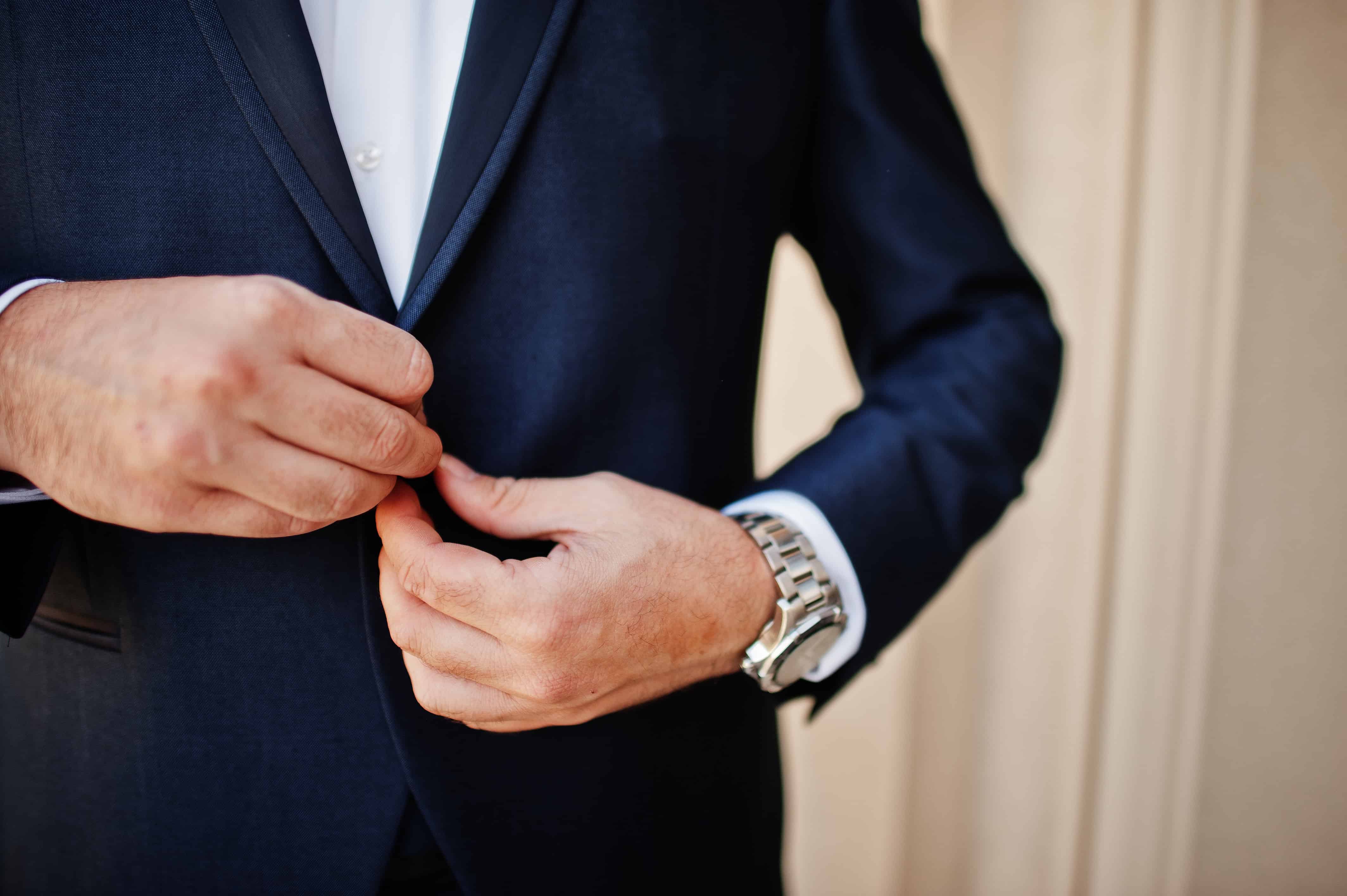 closeup of man adjusting suit jacket wearing silver watch