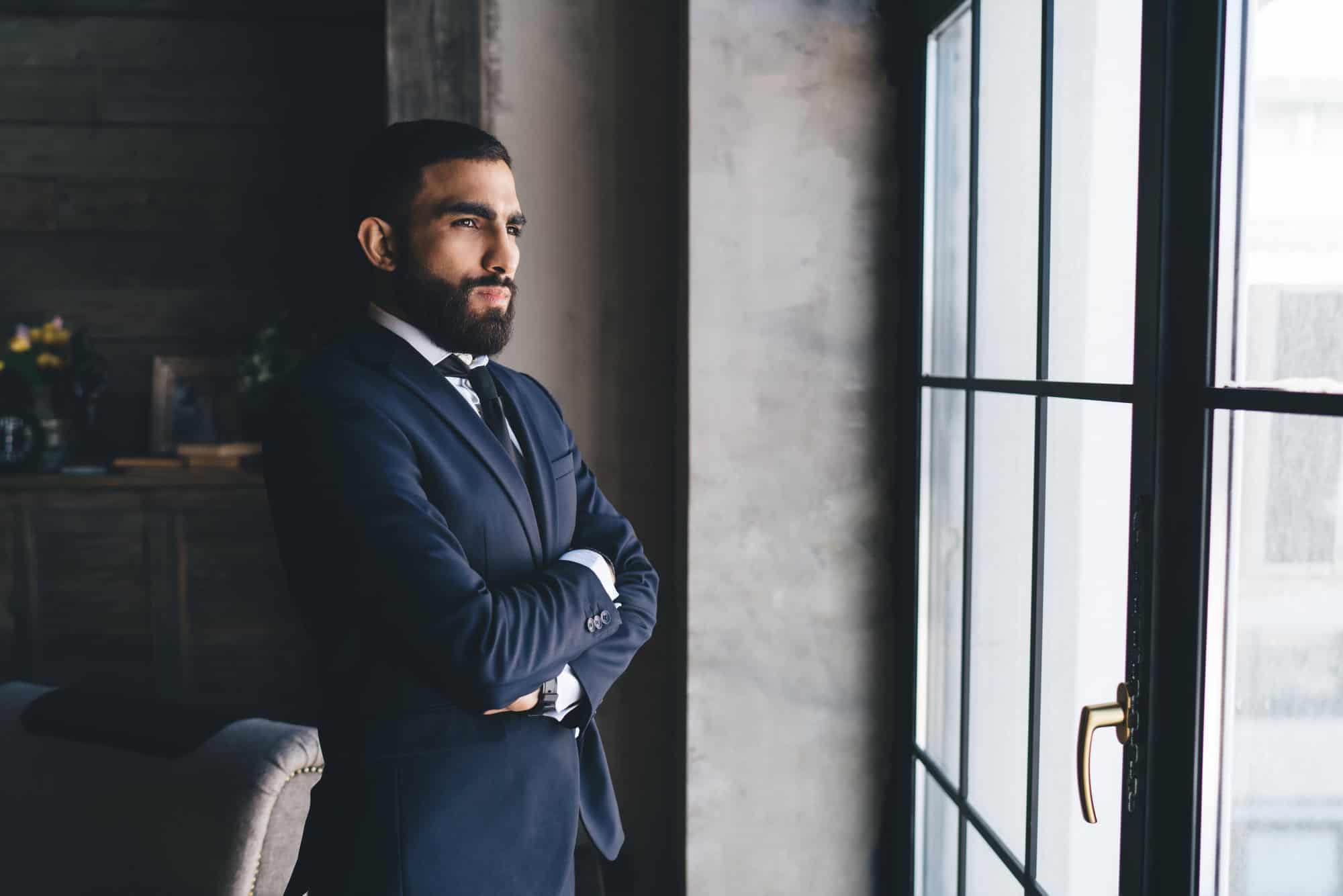 Man looking out window in dark suit