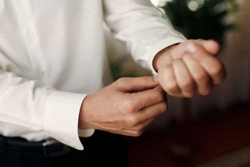 close up of man adjusting cuff of dress shirt