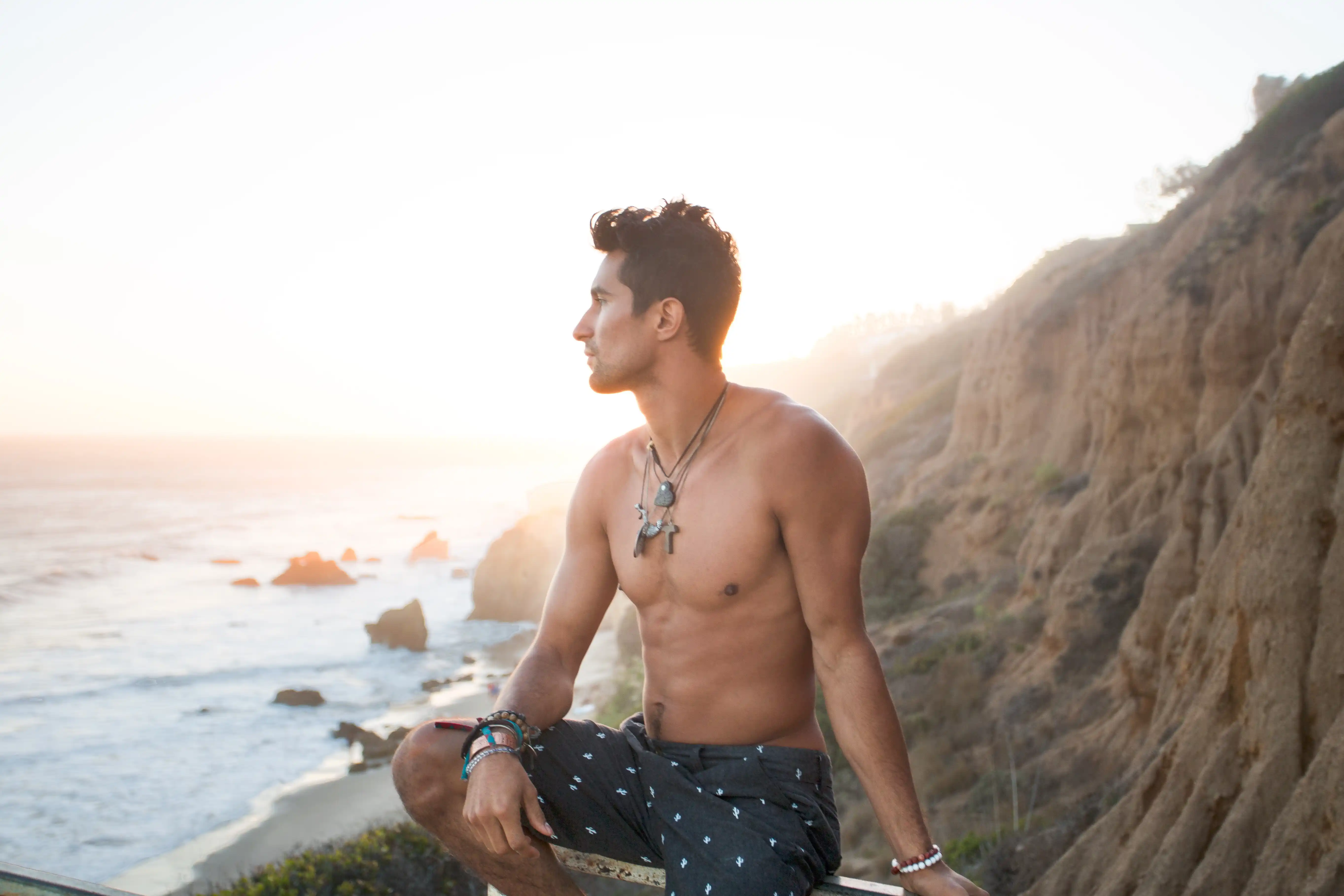 man in swim shorts looking out to ocean