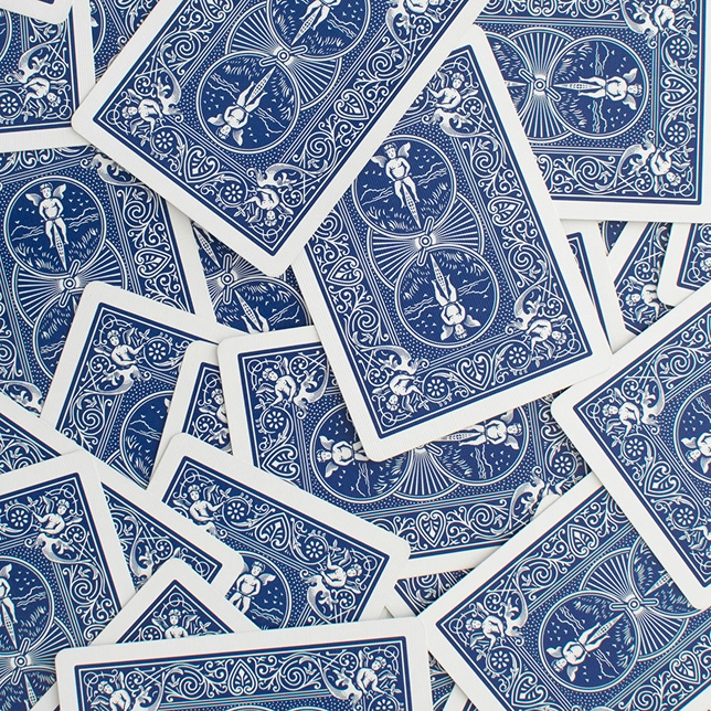 Scattered overlapping playing cards showing blue and white intricate back designs with angel and scroll motifs.