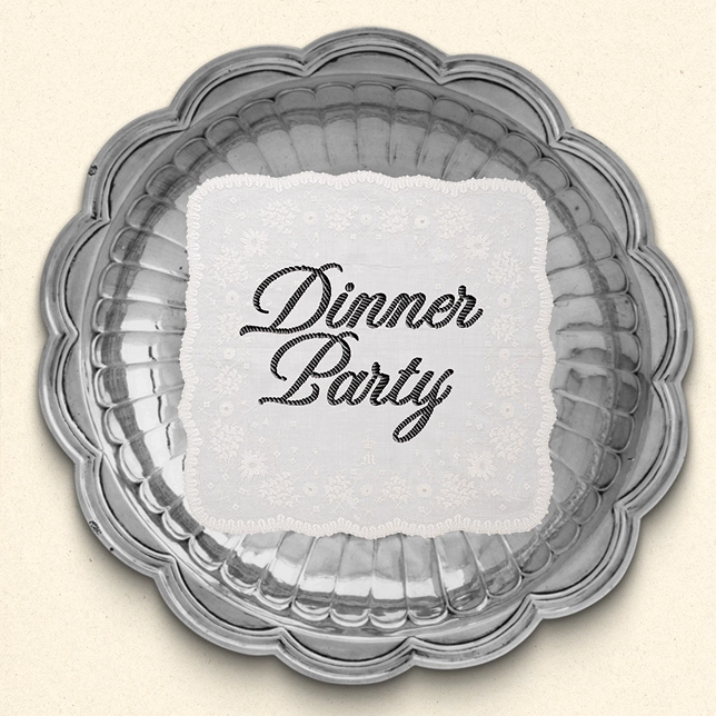 Silver scallop-edged platter with a white lace napkin in the center reading 'Dinner Party' in cursive.