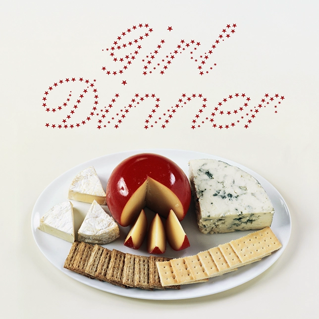 Plate of assorted cheeses and crackers under red star-lettered words 'Girl Dinner'.