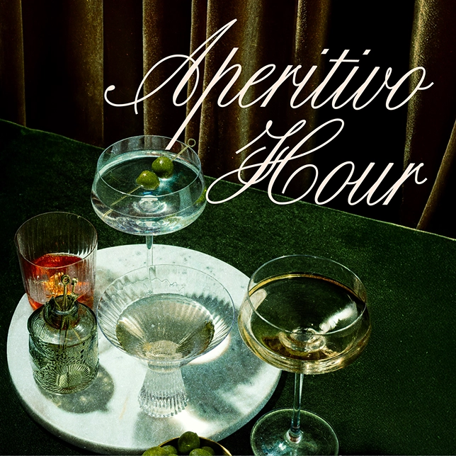 Four cocktail glasses on a white marble tray with olives, text reads Aperitivo Hour.