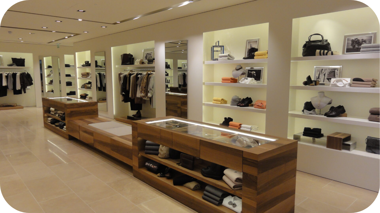 Upscale boutique with illuminated shelving, timber display counters, folded clothing, accessories, and modern minimalist interior design.