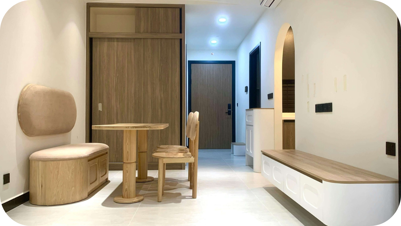 Compact apartment interior with custom joinery furniture including a wooden dining set and built-in seating.