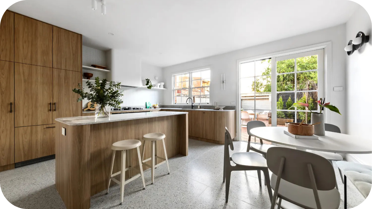 Luxury kitchen featuring custom timber cabinetry, marble island, and dining area filled with natural light from large windows.