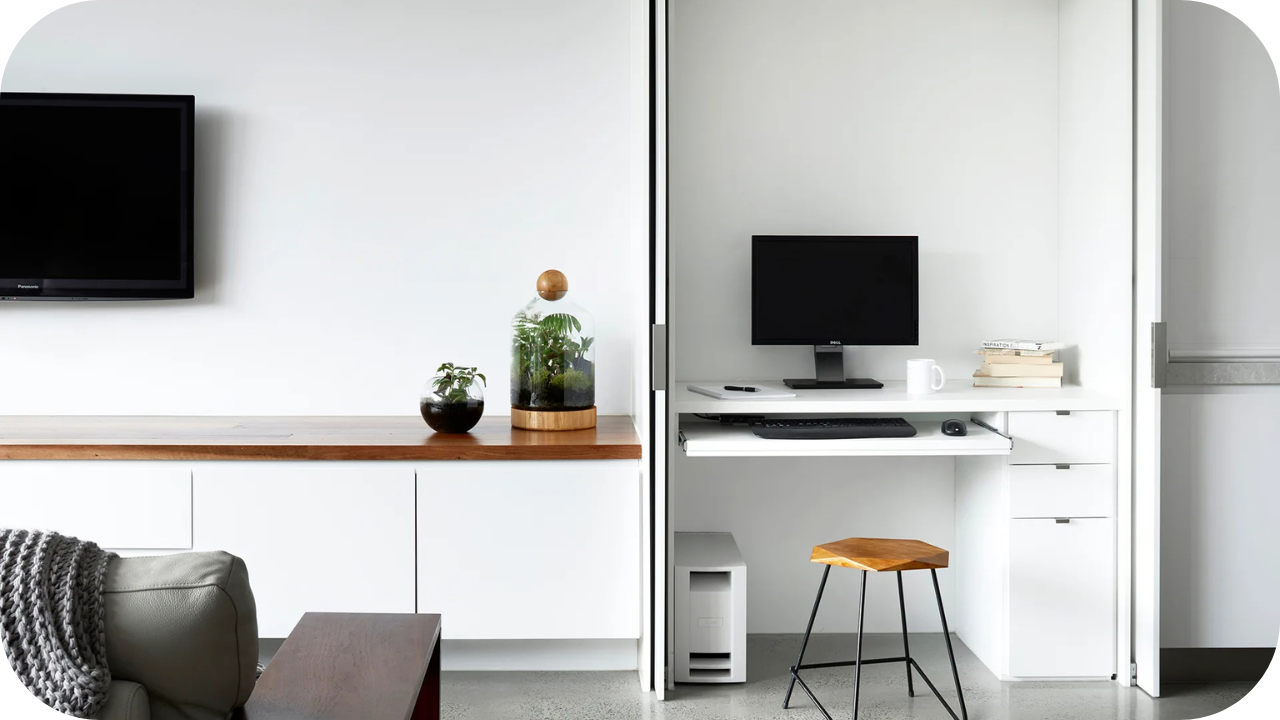 Minimalist open-plan living area with a hidden joinery office nook featuring a desk and storage.