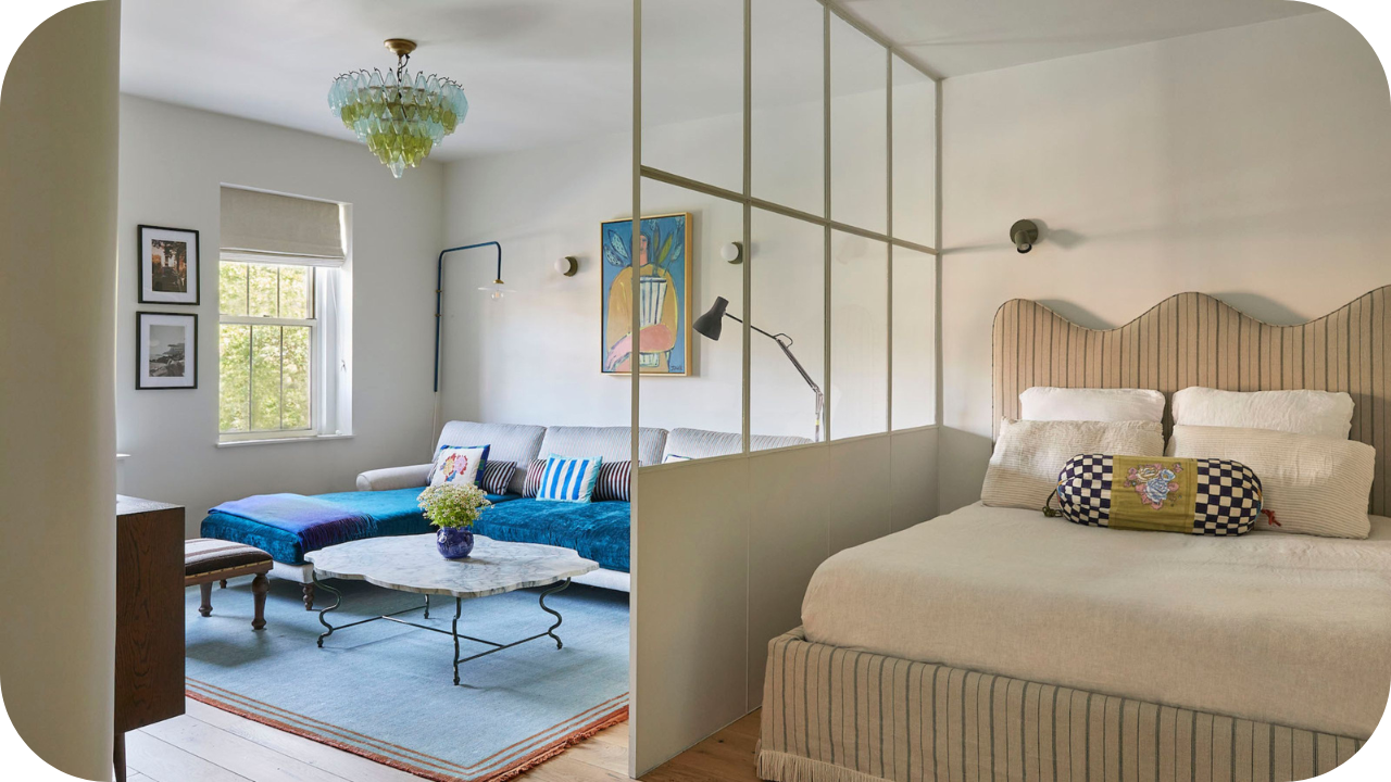 Open-plan bedroom with half-wall joinery divider separating bed from living area.