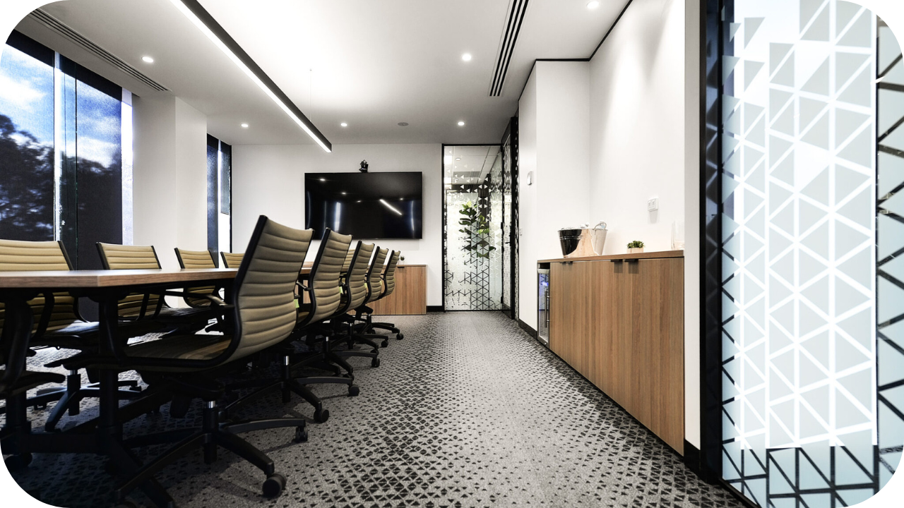 Modern conference room with long wooden table, leather chairs, and built-in cabinetry under wall-mounted TV.