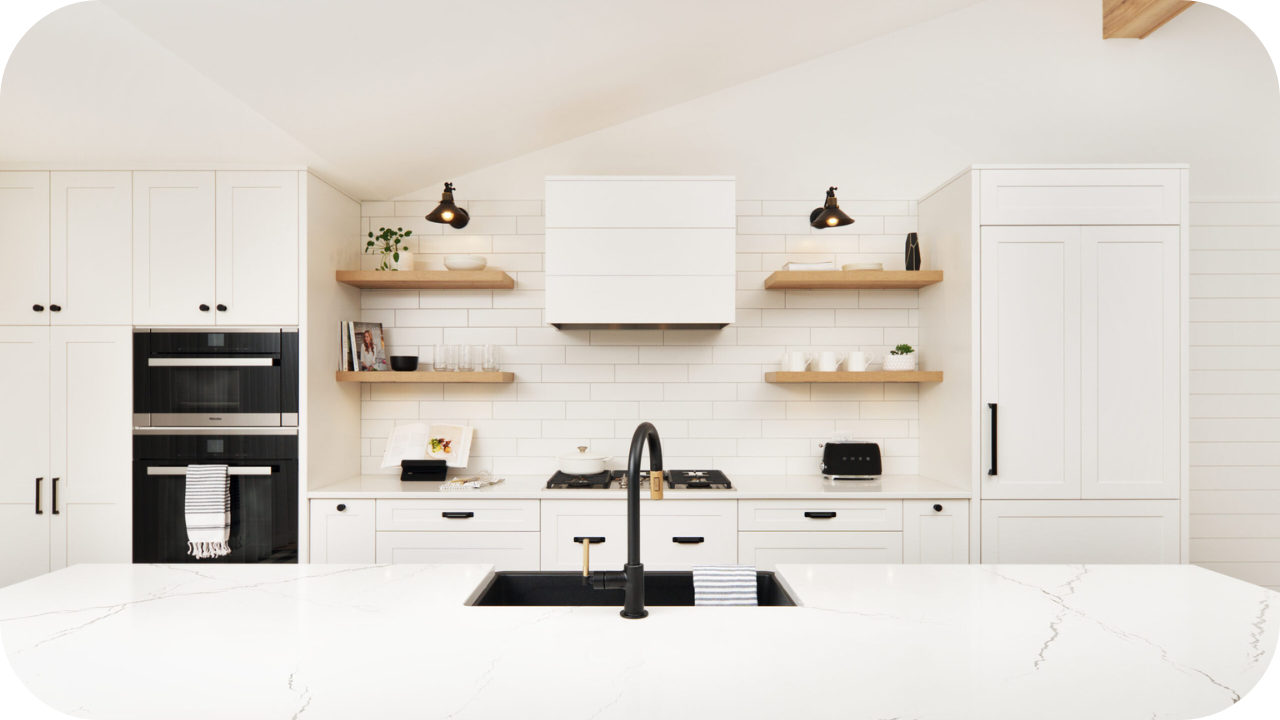 Minimalist white kitchen with marble countertops, open wooden shelves, and black fixtures designed for modern functionality.