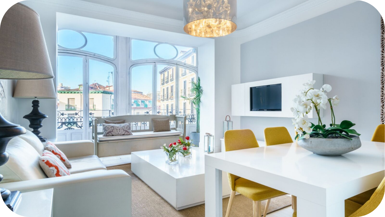 Modern living room with large arched windows, white furniture, yellow chairs, and bright natural lighting