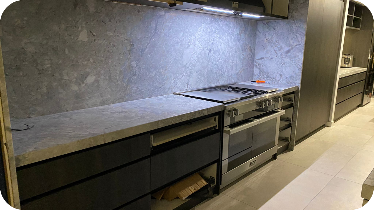 Partially installed modern kitchen joinery with stone benchtops, open drawers, and an oven fitted beneath for final adjustments.