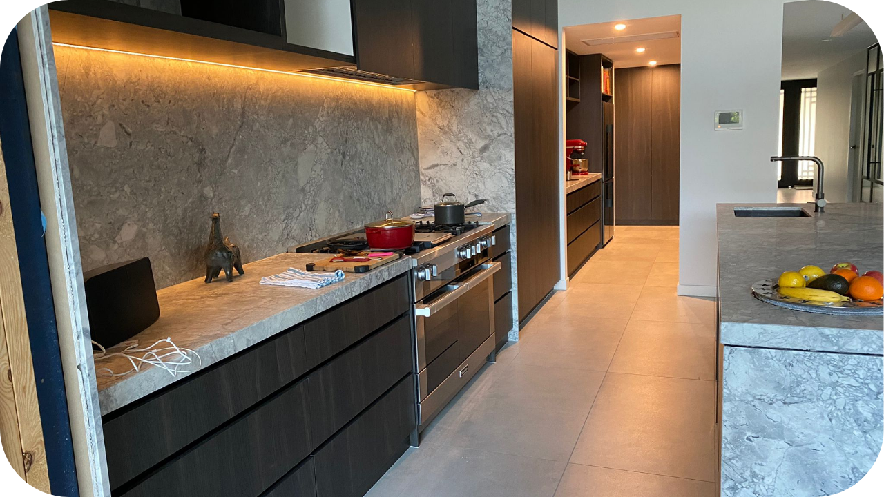 Contemporary kitchen with dark wooden cabinetry, marble countertops, integrated lighting, and a spacious layout, perfect for modern and minimalist design themes.