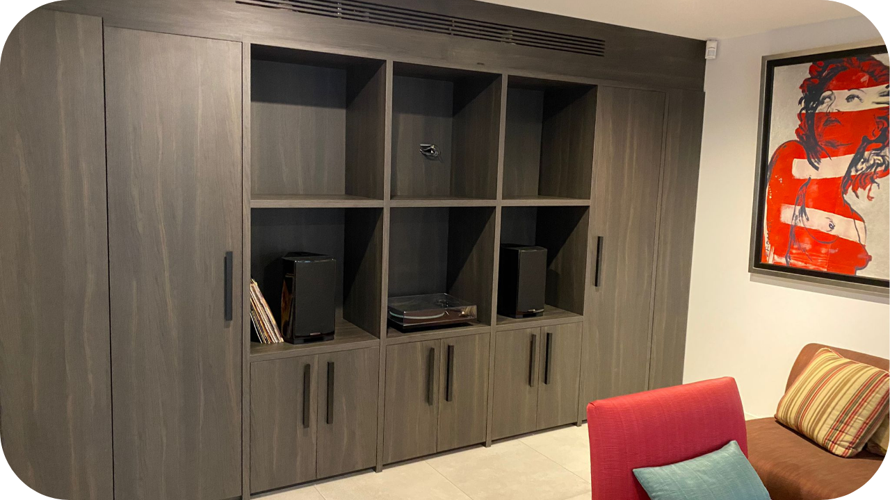 Modern living room with dark plywood joinery unit featuring open shelving, cabinets, and minimalist black handles for stylish storage.