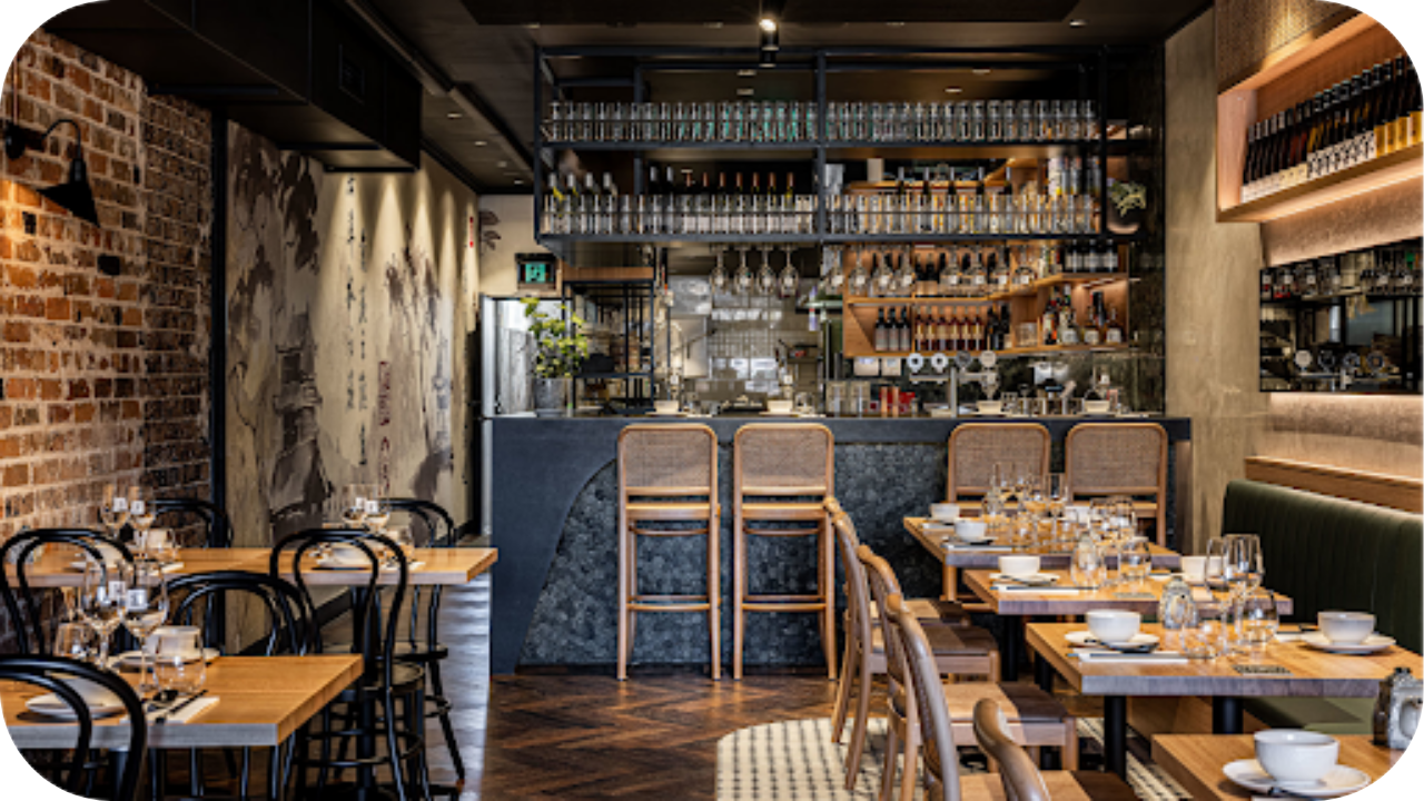 Modern restaurant featuring custom bar joinery, timber tables, shelving and warm lighting that creates an inviting dining atmosphere for guests