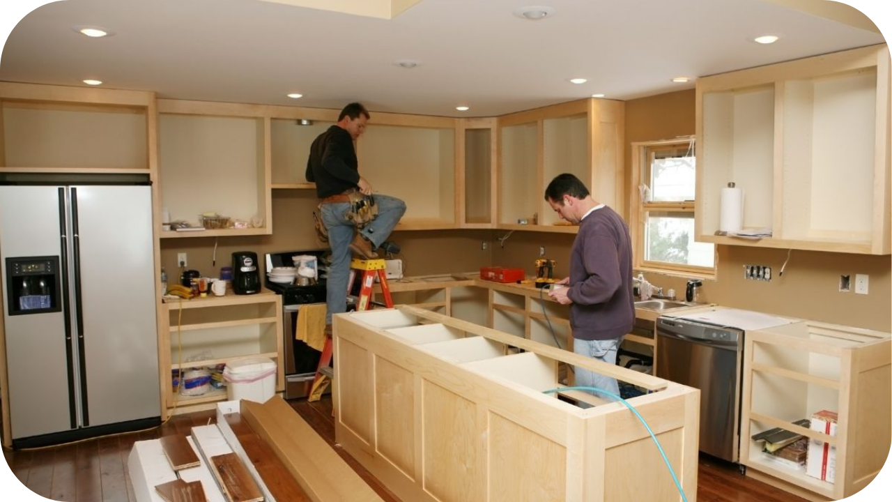 Two tradesmen installing custom kitchen joinery, adjusting cabinetry and fittings onsite to highlight how access, labour, and conditions affect joinery project pricing.