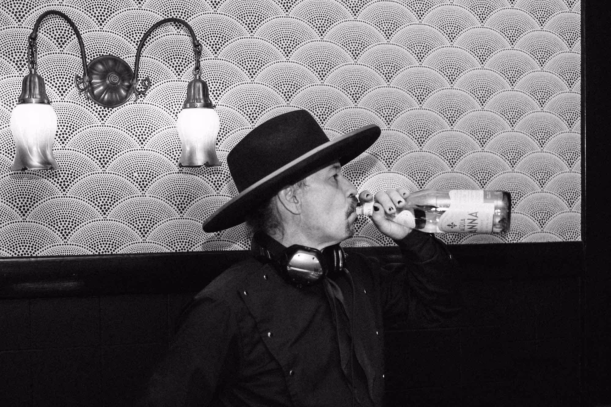 Black and white image of a DJ taking a swig from a clear tequila bottle during wedding reception at Edendale in Los Angeles.