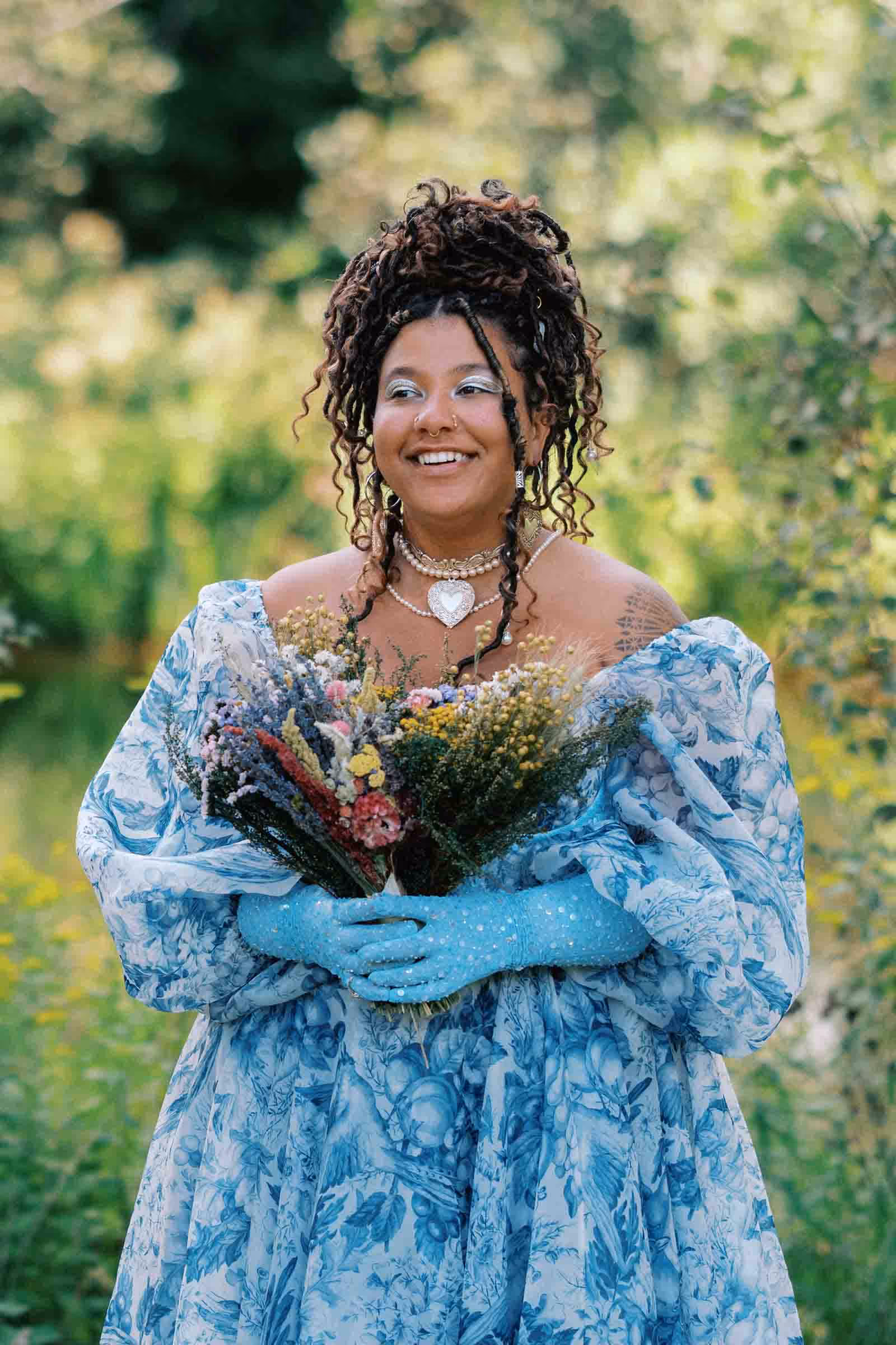 Bride in custom blue floral dress holding colorful bouquet of flowers at DIY wedding in Catskill Mountains.