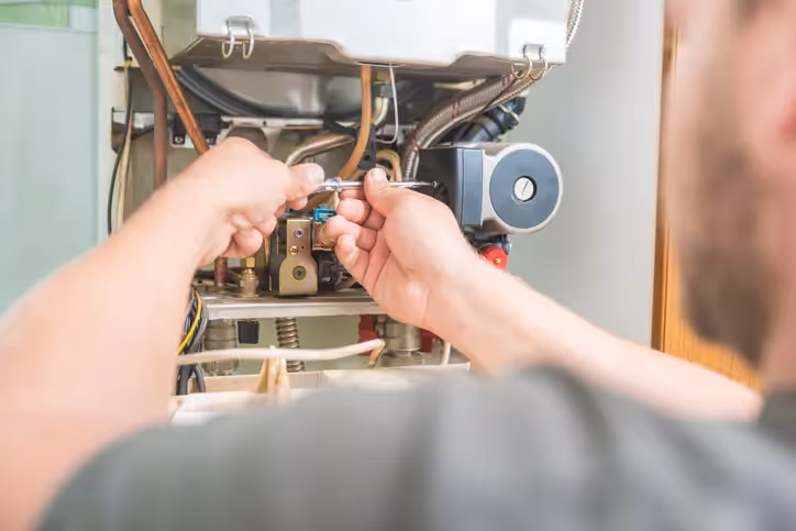 Man working on heater system with tools.