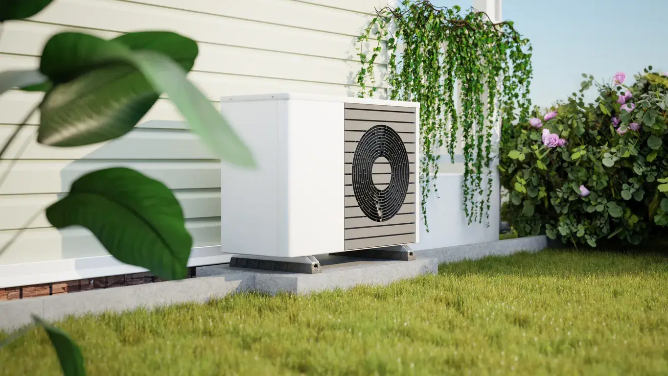 Sleek white air source heat pump unit installed on a concrete base next to a modern home.