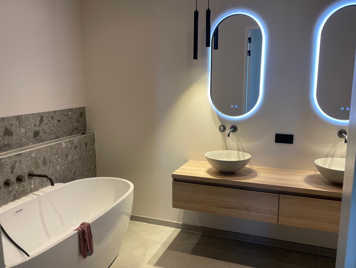 Badkamer met bad en moderne spiegels.