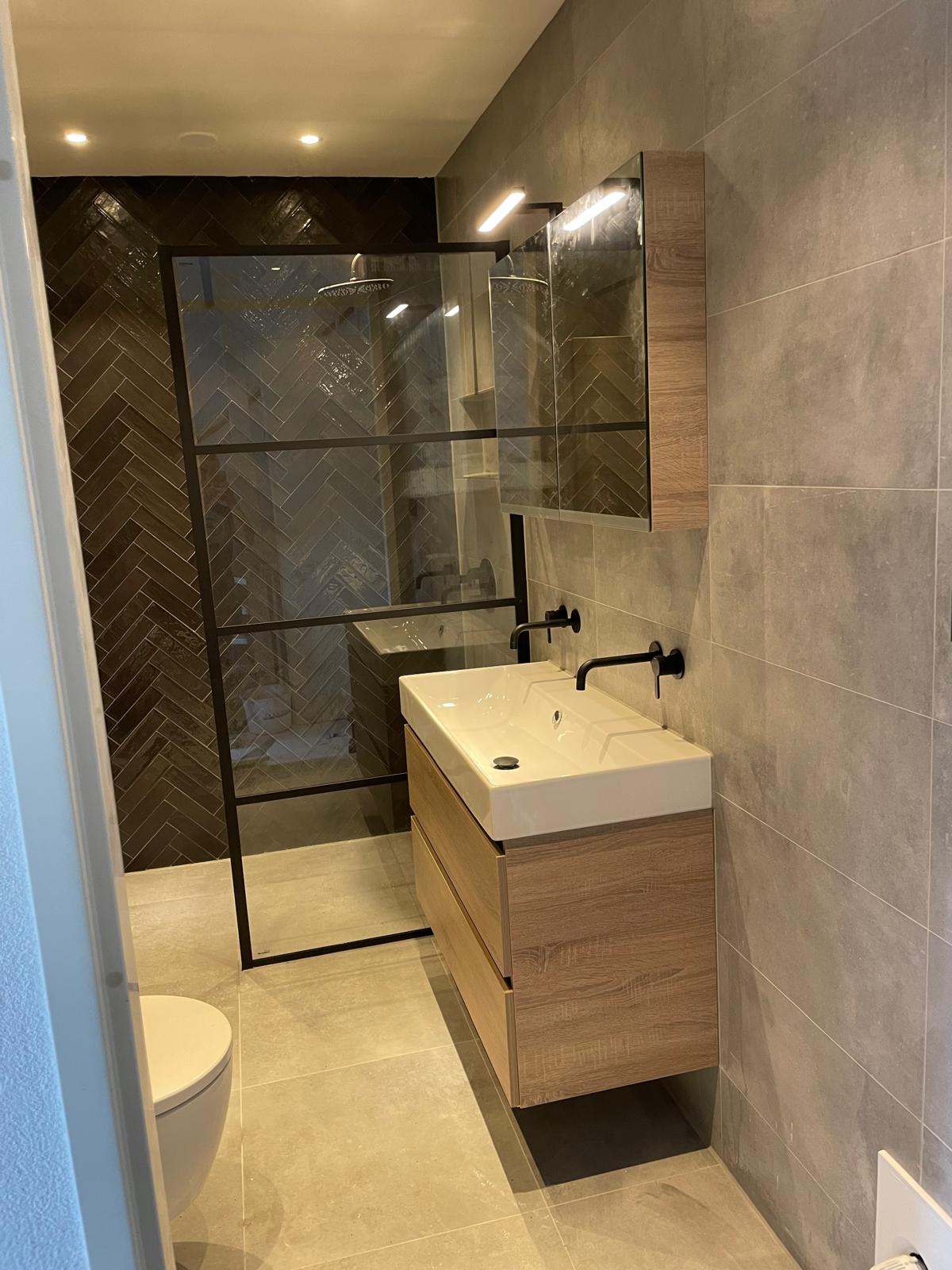 Badkamer met houten accenten en vissengraat muur.