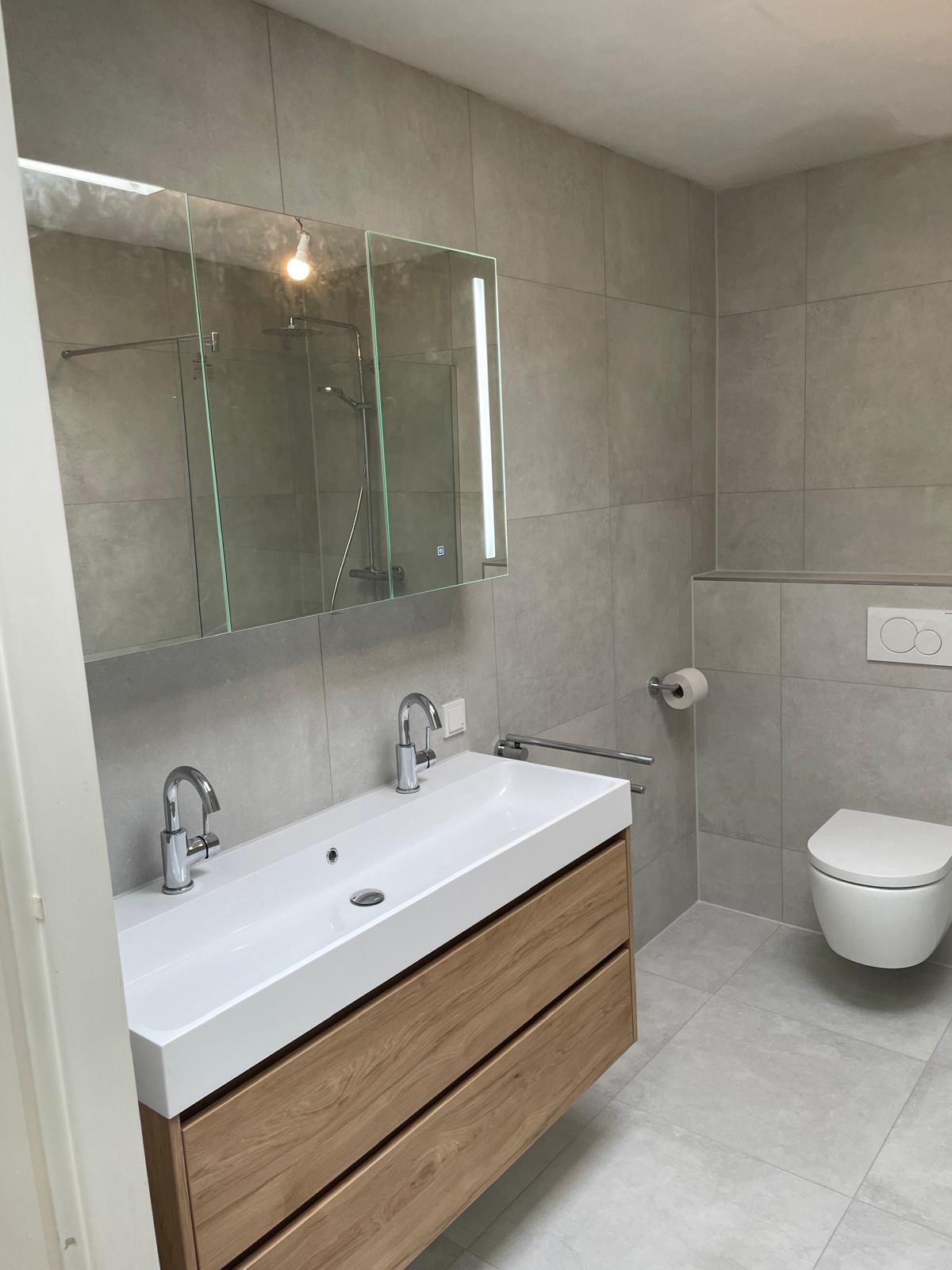 Badkamer met grijze tegels en houten accenten