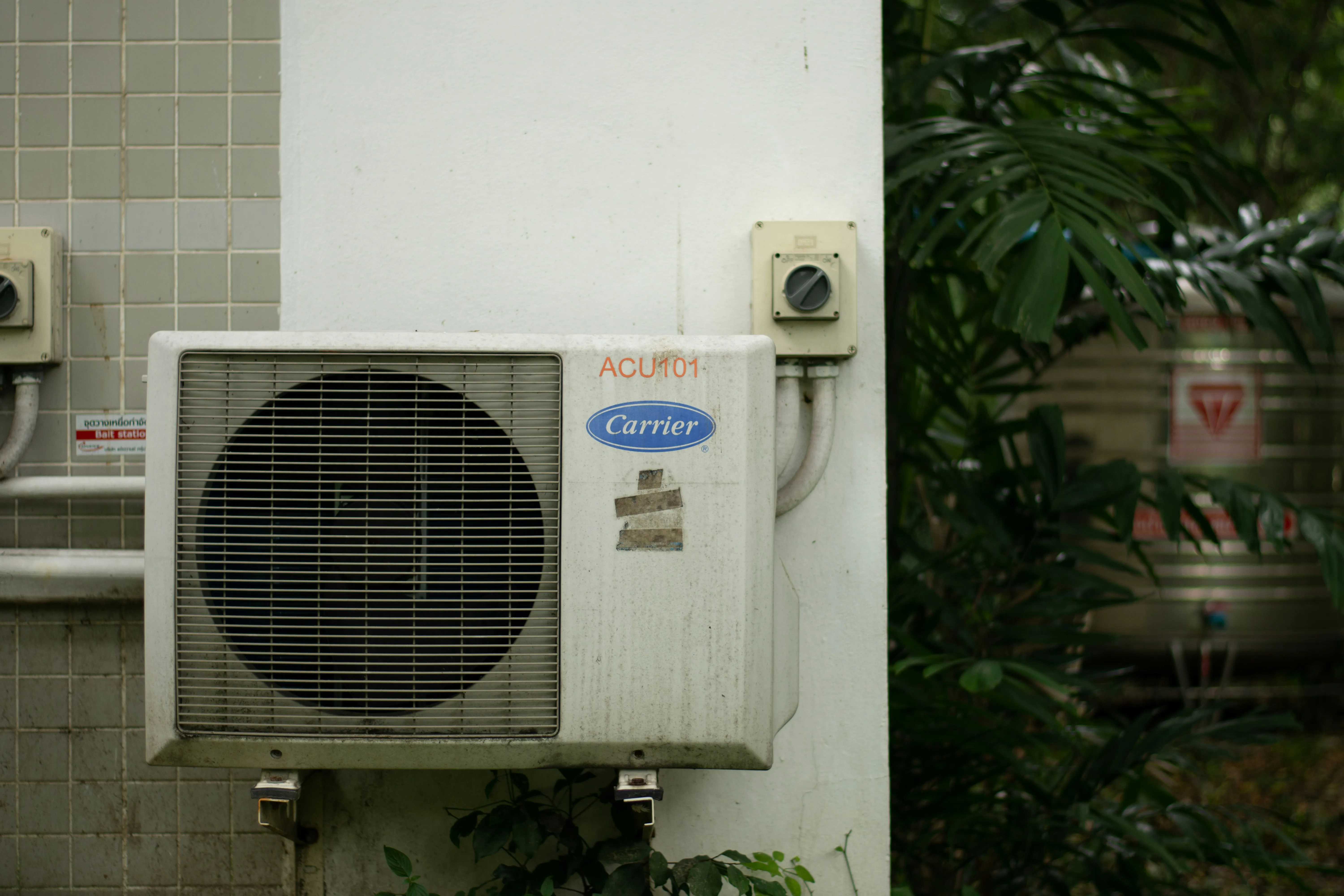 Carrier outdoor AC unit on a tiled wall.