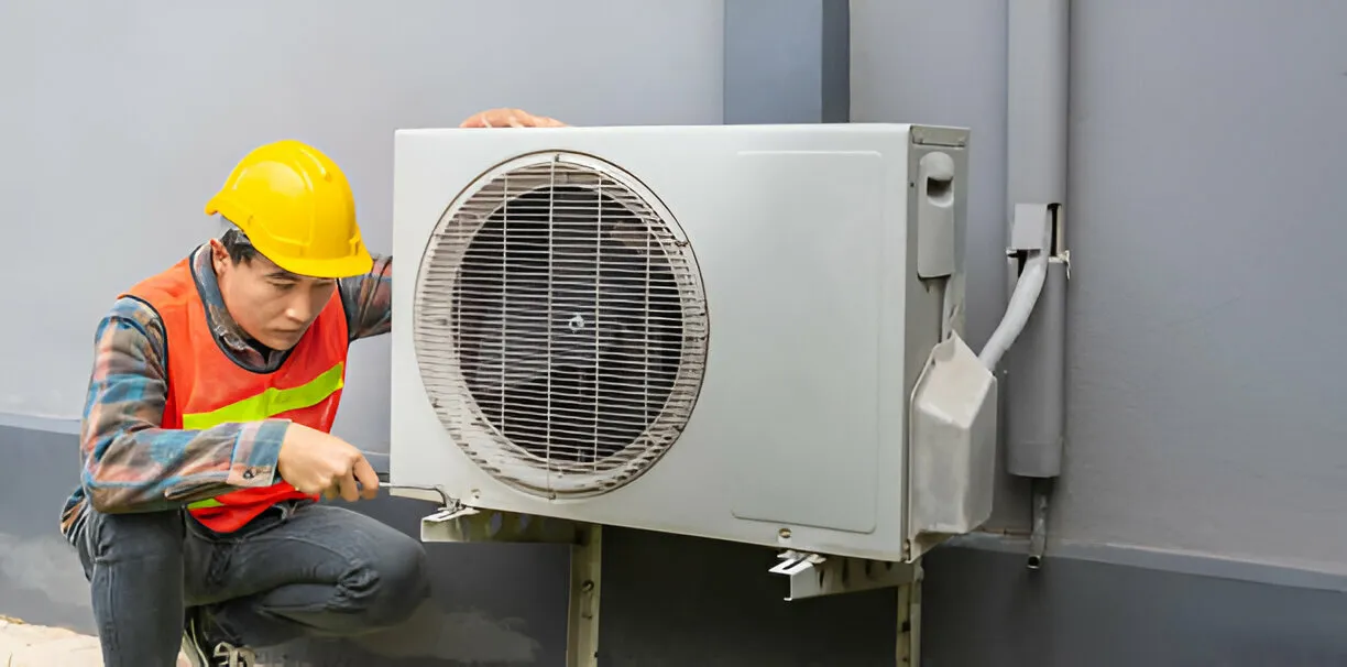 Man in hard hat repairing outdoor AC.