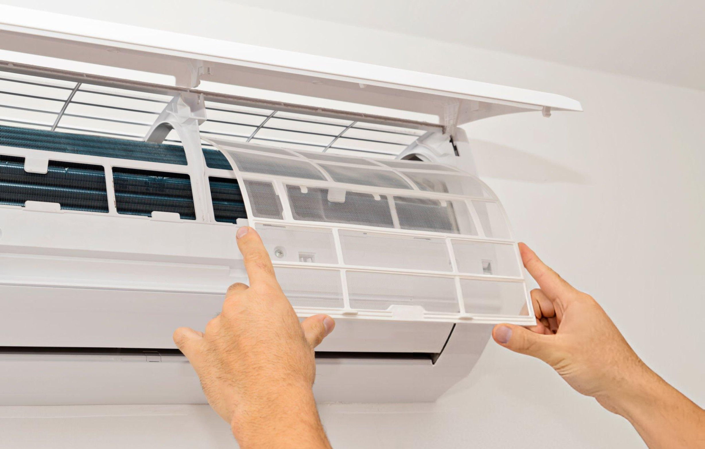 Hands opening air conditioning filter on wall-mounted unit
