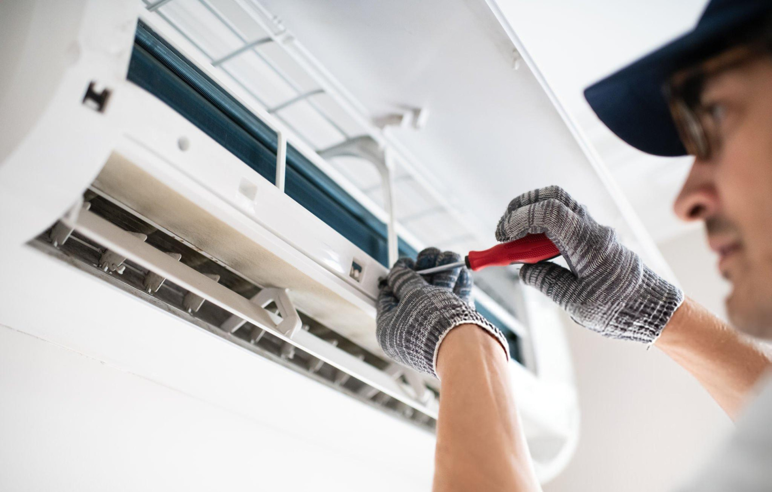 Technician fixing air conditioning unit with screwdriver