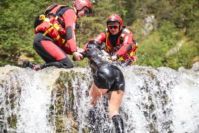 Water rescue team helping a female athlete up the waterfall obstacle at the X-Warriors race in Molveno