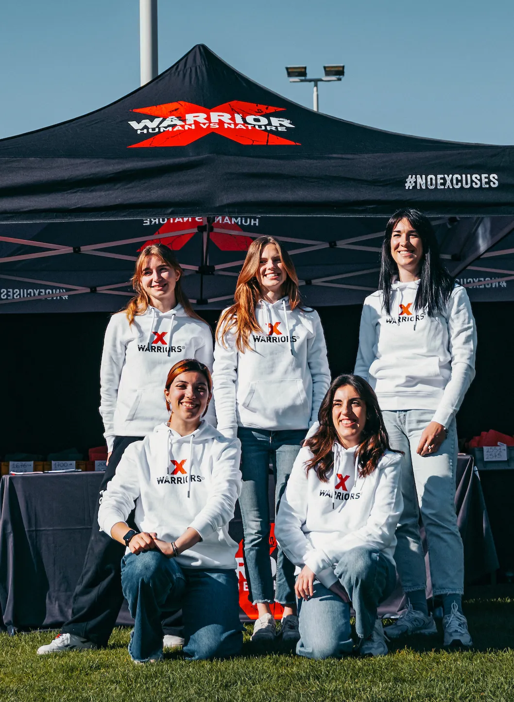 X-Warriors race office crew in team hoodies posing in front of the event tent in Molveno