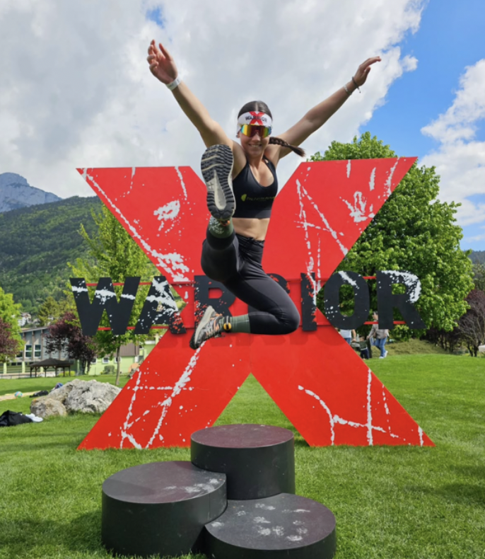 Woman Jumping of a podium with "x-warriros" event background 