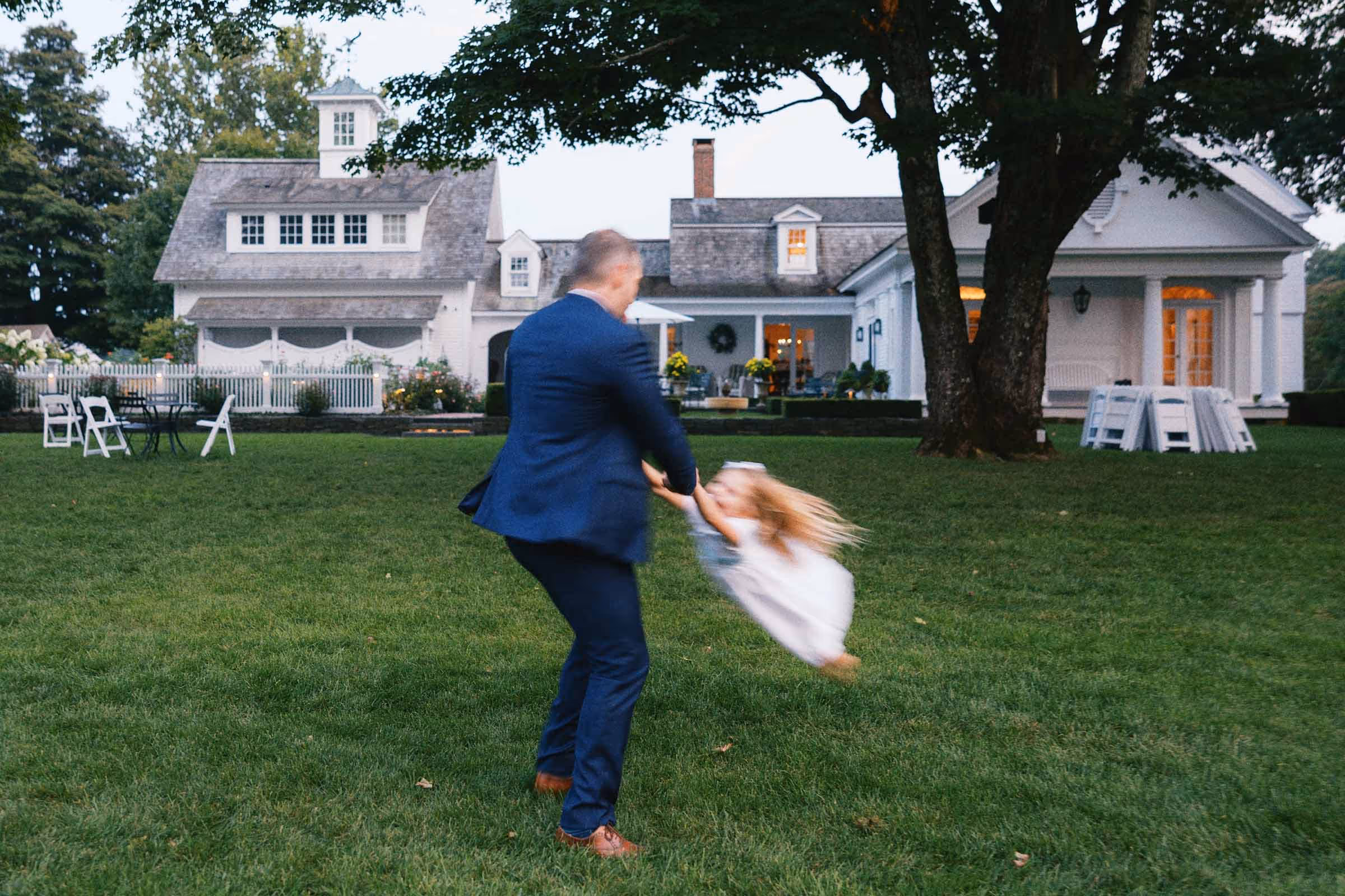 Motion-blur image of a wedding guest swinging his daughter around during a wedding reception at Smith Farm Gardens in Connecticut 