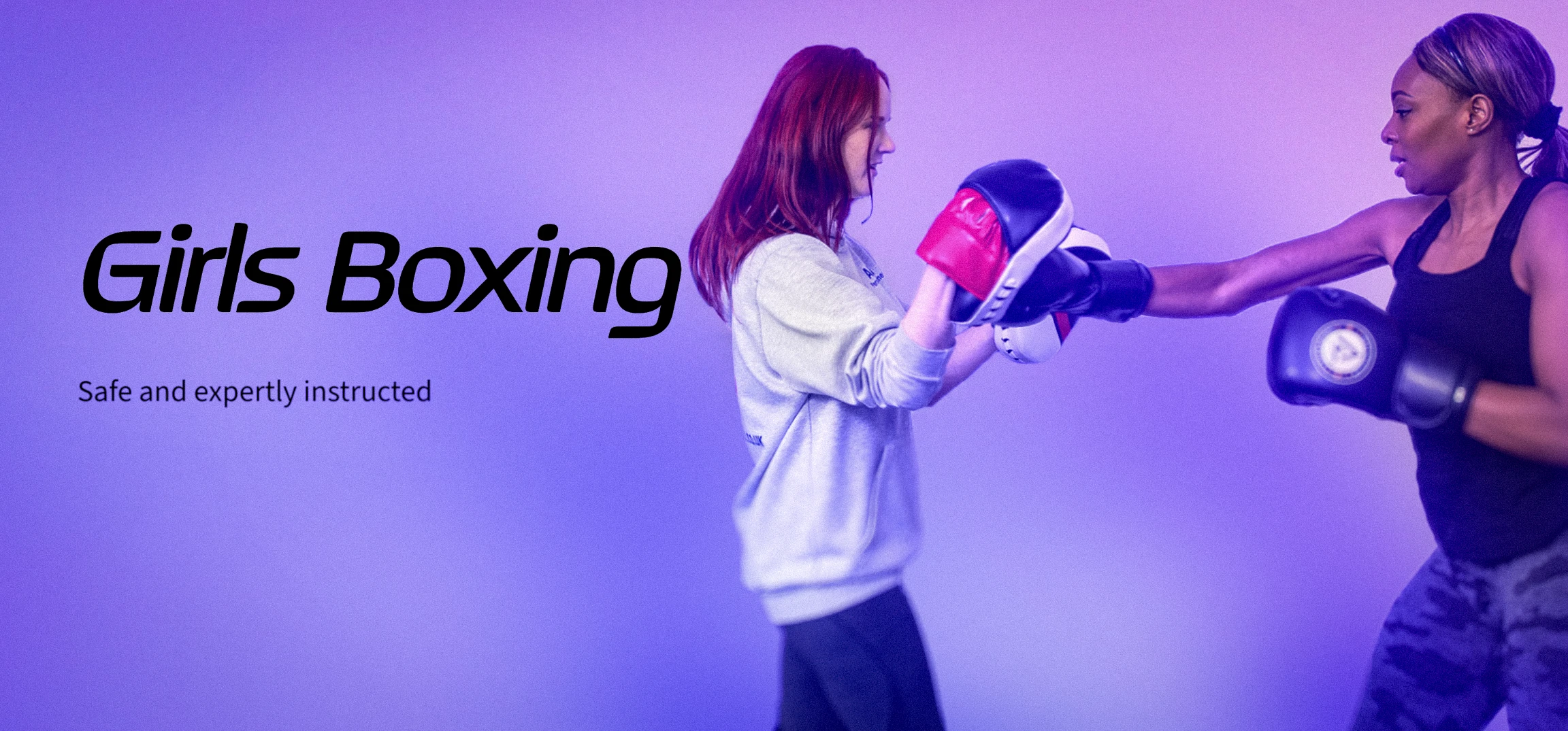 Two women boxing together, one holding pads and one wearing gloves, from Alison Berrisford's Girls Boxing sessions.