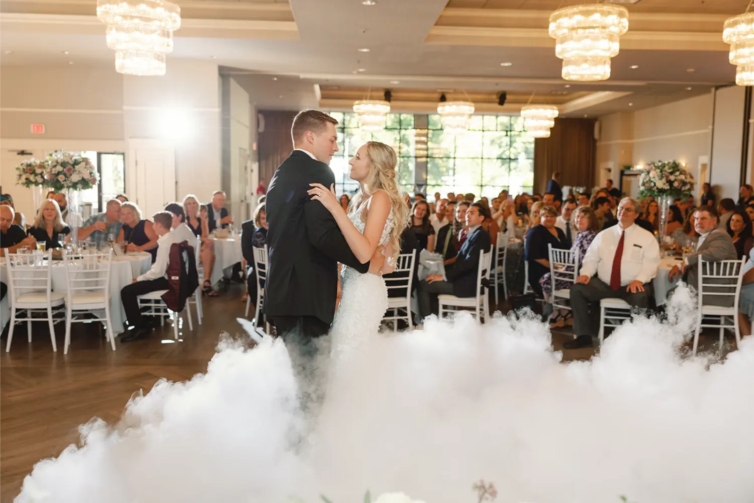 A bride and groom dance in front of a crowd of people.